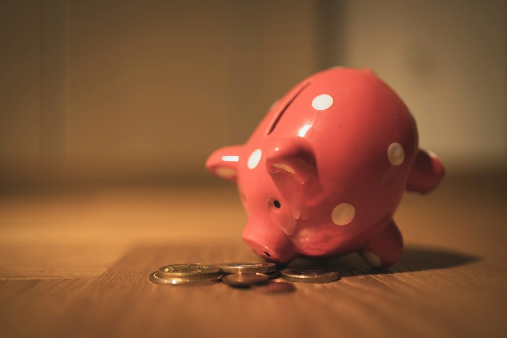 Photo by Andre Taissin pink pig coin bank on brown wooden table